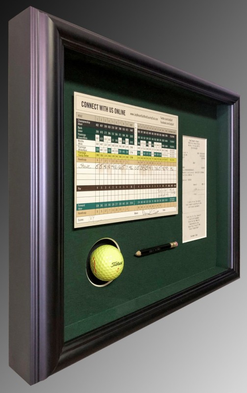 Side view of picture frame with golf ball and score card